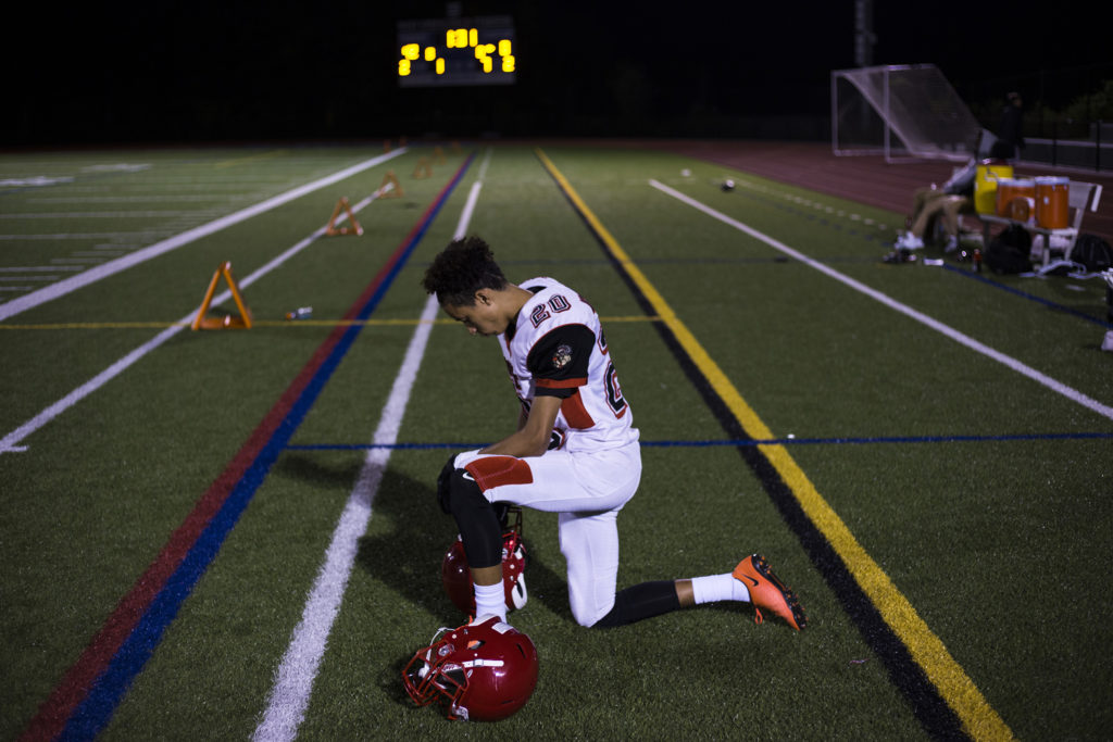 Wide receiver, David Porche Mayes, of the High School of Commerce kneels as he waits for the clock to run out as his team faces a 0-42 half-time score during a game in West Springfield, Mass., on Friday, September, 8, 2017. (Photo by Brittany Greeson)