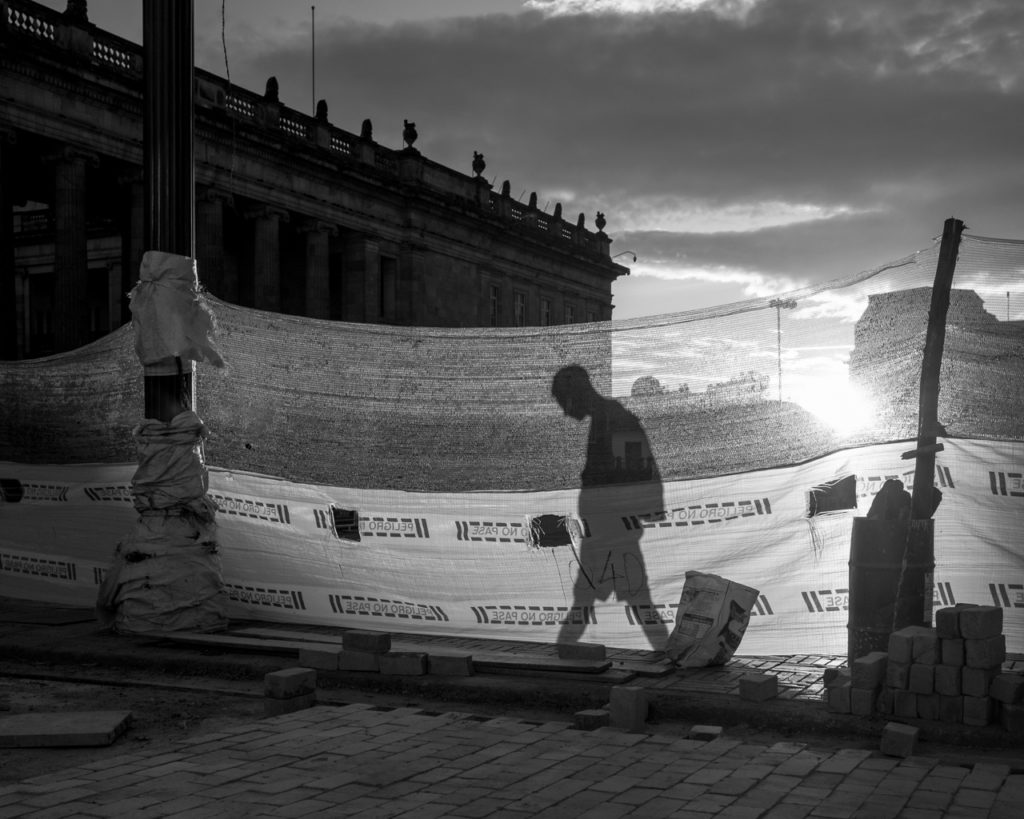 A man walks behind a construction barrier in the Plaza de Bolivar. In the background, the Colombian Congress Building. July 25, 2015. (Juan Cristóbal Cobo/The GroundTruth Project)