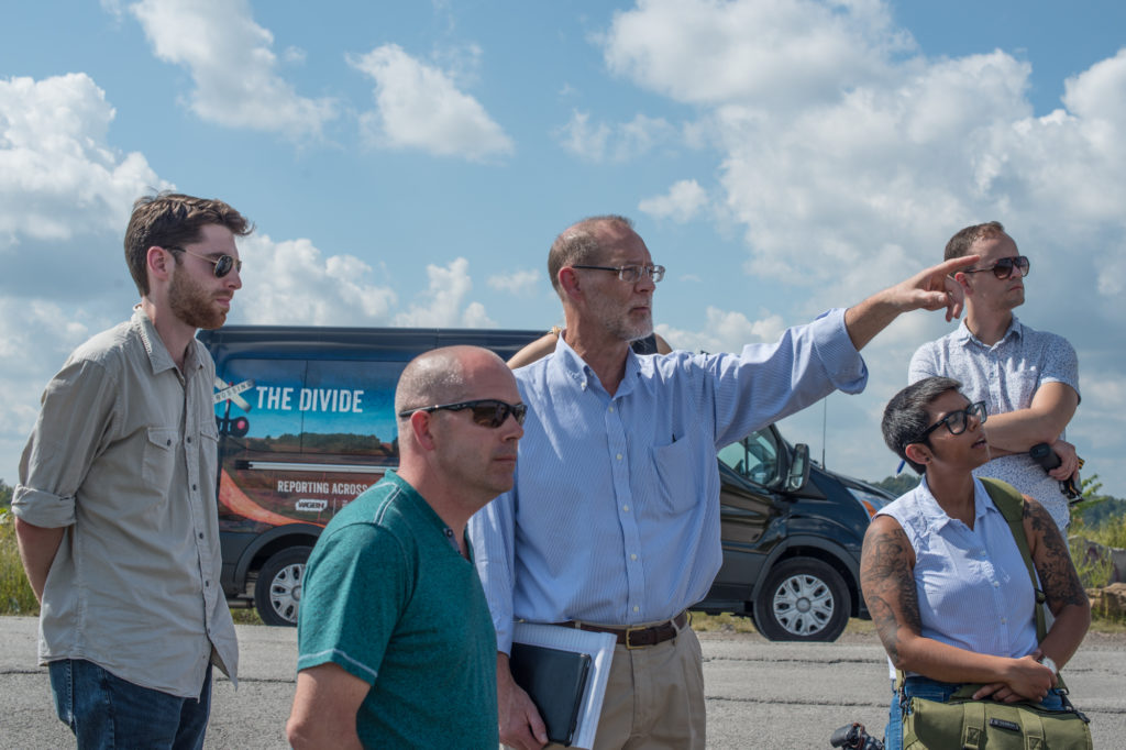 Bill Estep, (pointing, center) facilitated a visit to the site of a former strip mine. Also pictured, from left: Eric Bosco, former coal worker Kenny Stanley, Qainat Khan and Gabriel Sanchez. (Photo by Ben Brody/GroundTruth)