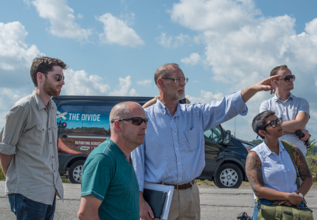 Bill Estep, (pointing, center) facilitated a visit to the site of a former strip mine. Also pictured, from left: Eric Bosco, former coal worker Kenny Stanley, Qainat Khan and Gabriel Sanchez. (Photo by Ben Brody/GroundTruth)