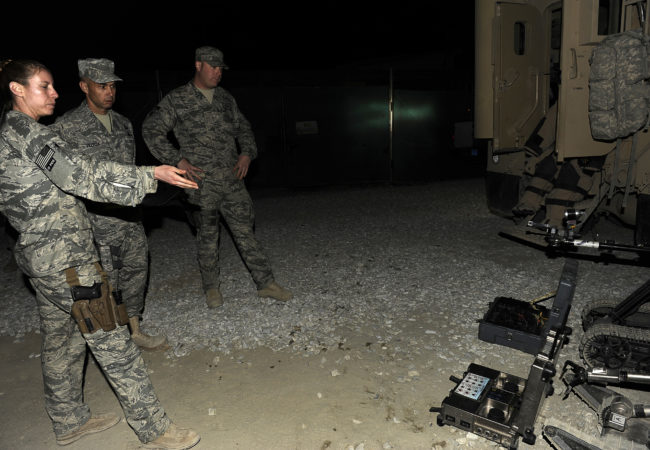 U.S. Air Force Staff Sgt. Elizabeth Butler was one of the few women bomb techs on the Explosive Ordnance Division of the Air Force. She demonstrates a Packbot, a robot that helped her and her team disable IEDs, at Bagram Airfield in Afghanistan on Dec. 29, 2009. (Photo courtesy of Elizabeth Butler)