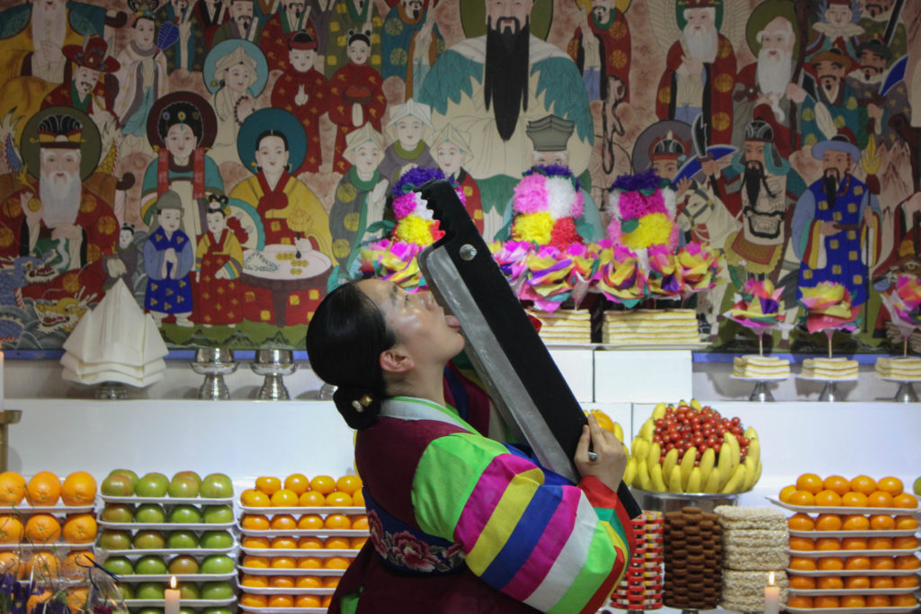 One of the shamans, who chose not to share her name, showed Choi that she had incarnated one of the gods by licking a sharpened blade and then balancing it on her throat. (Miranda Mazariegos/GroundTruth)