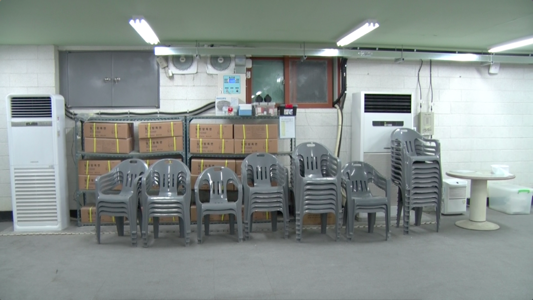 Plastic chairs, gas masks, and a Phillips CD player are stored for emergencies at an underground shelter near Tongil Chon's city hall. (Aziza Kasumov/GroundTruth)