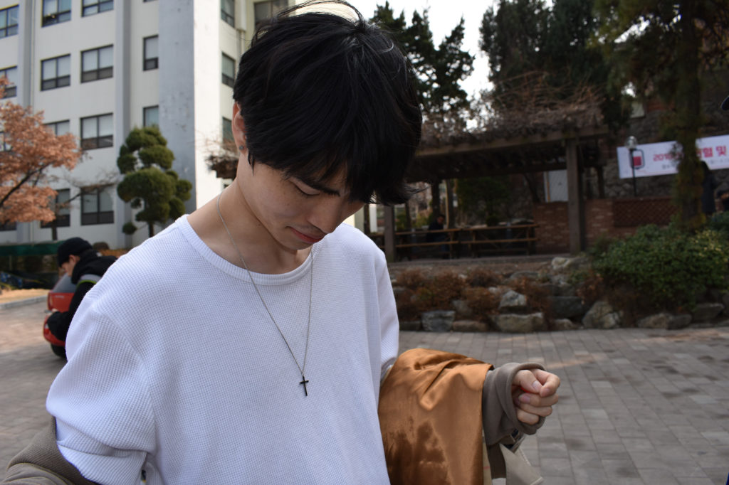 Lim doesn’t believe in God, Jesus, or any religion, but he wears his Christian grandfather’s cross as a good luck charm. (Ashley Vazquez/GroundTruth)