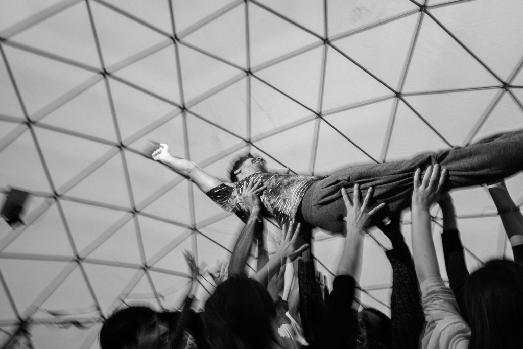 During a February 15 workshop in The Dome, people take turns doing group trust falls. One person teeters slightly and the group catches them, then falls slightly more, and then at last falls fully into the waiting hands of the others who lift them up and carry them around the space. (Photo by Annabelle Marcovici/GroundTruth)