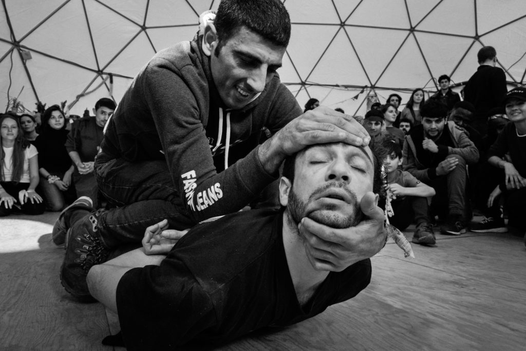 French breakdancer and choreographer Sofian Jouini (bottom) performs with another man during the March 3 Hope Show. Moments beforehand, Sofian had collapsed on the ground dramatically in the middle of a group performance. The crowd reacted by falling silent and clearing away from him while others, including the man pictured here, appeared to rush to his aid. For a time it was unclear whether this was part of the show, but slowly the man massaged, pulled, and prodded Sofian back to life. People watched rapt as the playfulness returned and Sofian's performed self was revived. (Photo by Annabelle Marcovici/GroundTruth)