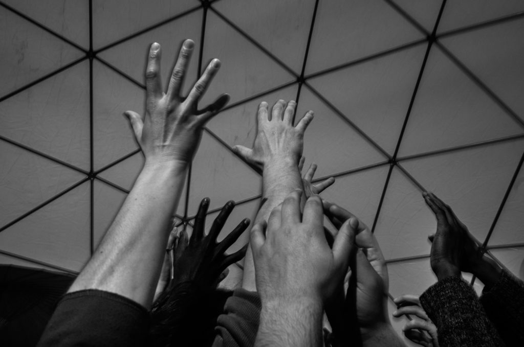 Participants in a contact improvisation workshop in Good Chance's larger Dome gather close together and reach skyward, forming a single, collective gesture with their bodies. (Photo by Annabelle Marcovici/GroundTruth)