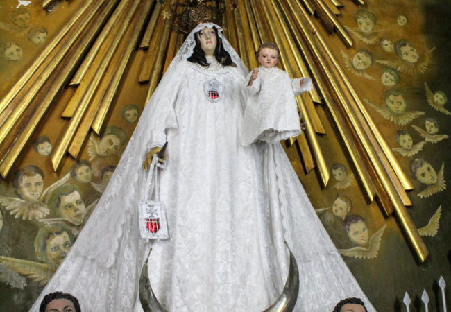 The image of Saint Mercedes, mounted a flight of stairs above the altar at Our Lady of Mercy church, is the reason many Santería practitioners visit. When they look at the image, they see Obatalá, the parent of all orishas. Yojander Pérez López, a volunteer at the church, said it can be frustrating when people enter and call the statue by the orisha’s name. “She is not Obatalá, she is the mother of Christ,” he said. (Photo by Paxtyn Merten/The GroundTruth Project)