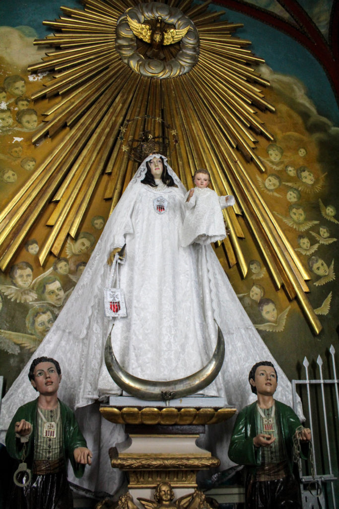 The image of Saint Mercedes, mounted a flight of stairs above the altar at Our Lady of Mercy church, is the reason many Santería practitioners visit. When they look at the image, they see Obatalá, the parent of all orishas. Yojander Pérez López, a volunteer at the church, said it can be frustrating when people enter and call the statue by the orisha’s name. “She is not Obatalá, she is the mother of Christ,” he said. (Photo by Paxtyn Merten/The GroundTruth Project)
