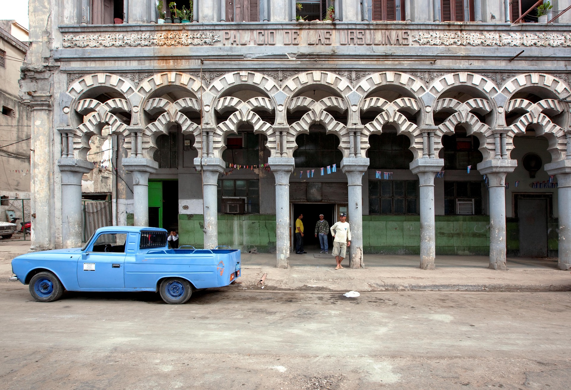 A man stands on the street next to a vintage car in Cuba. (Photo by Falkenpost/Pixabay)