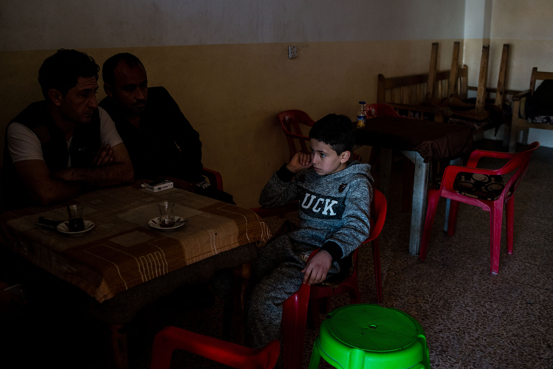Dilshad sits in a cafe with his father and a family friend. He was recently released from ISIS captivity after his family bought him back. (Alex Potter/GroundTruth)