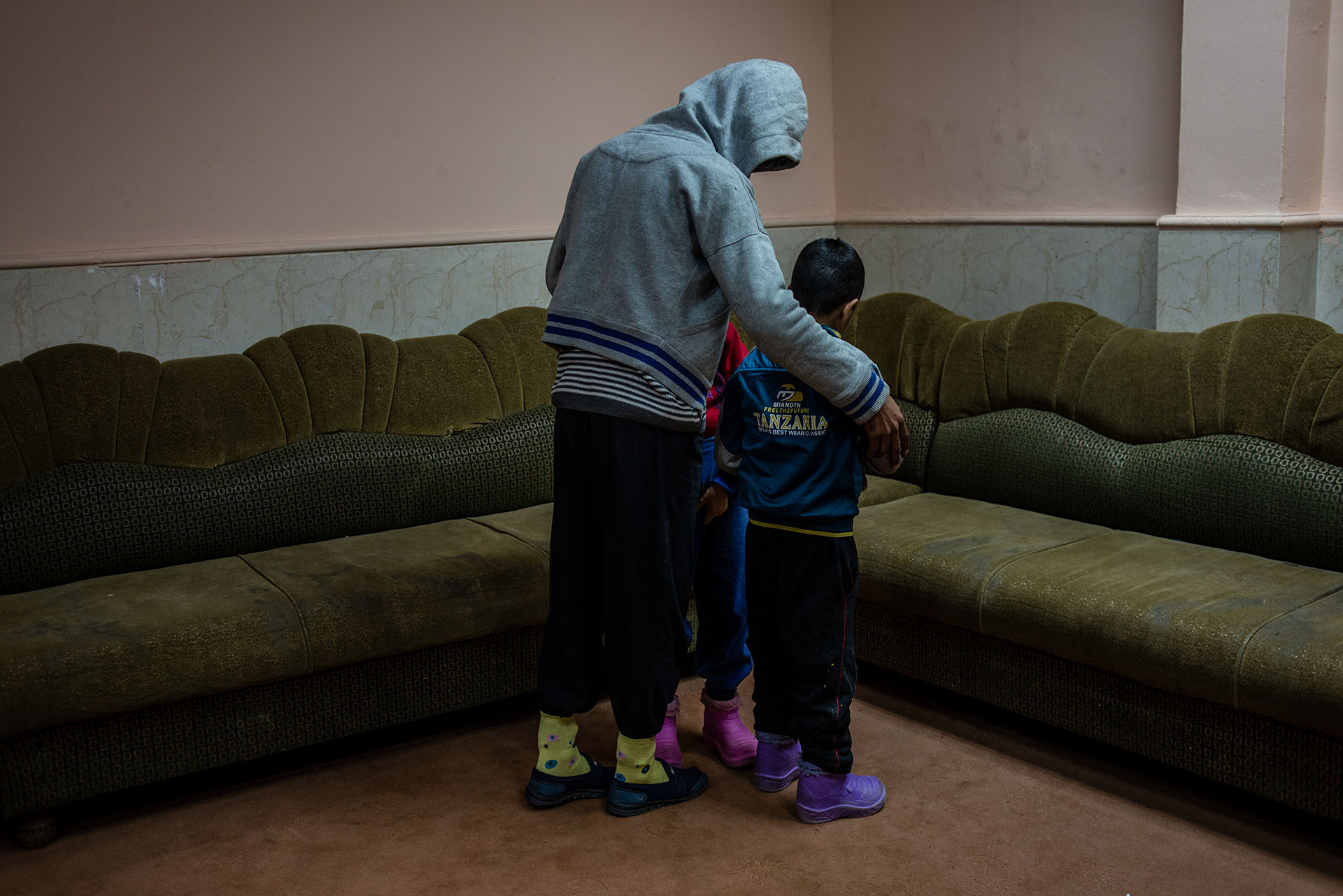 Two disabled boys, found wandering around playground city alone, are shielded by an older resident at the Mosul orphanage. (Alex Potter/GroundTruth)