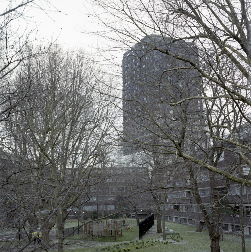 The skeletal remains of Grenfell Tower stands behind the Lancaster Estate, whose occupants still grieve over the loss of their friends and family who perished in the fire.