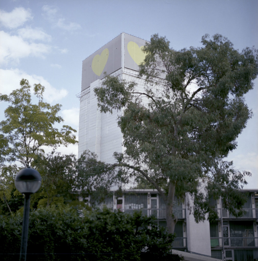 Grenfell Tower's remains are completely covered by a white tarp, with a memorial heart at the top of the tower - requested by the local residents, families and survivors of the fire. (June 14th 2018)