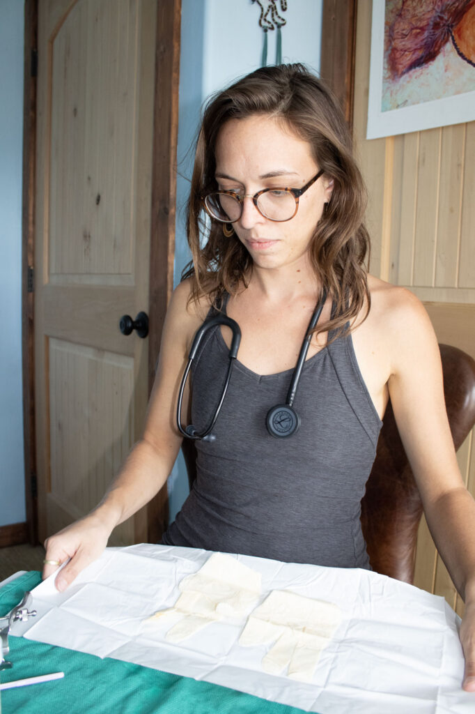 Midwife Jaime Doty unwraps a fresh set of gloves while sitting in her home, where she often sees patients throughout the pregnancy process. (Photo by Kylea Henseler/GroundTruth)