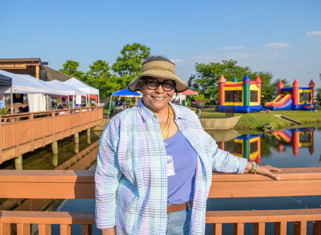 A woman with a sunhat and glasses poses for a portrait.