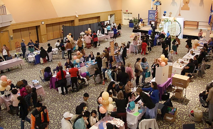 This is an overview photo of a community baby shower where many different organizations have booths and tables to talk to and prepare new parents.