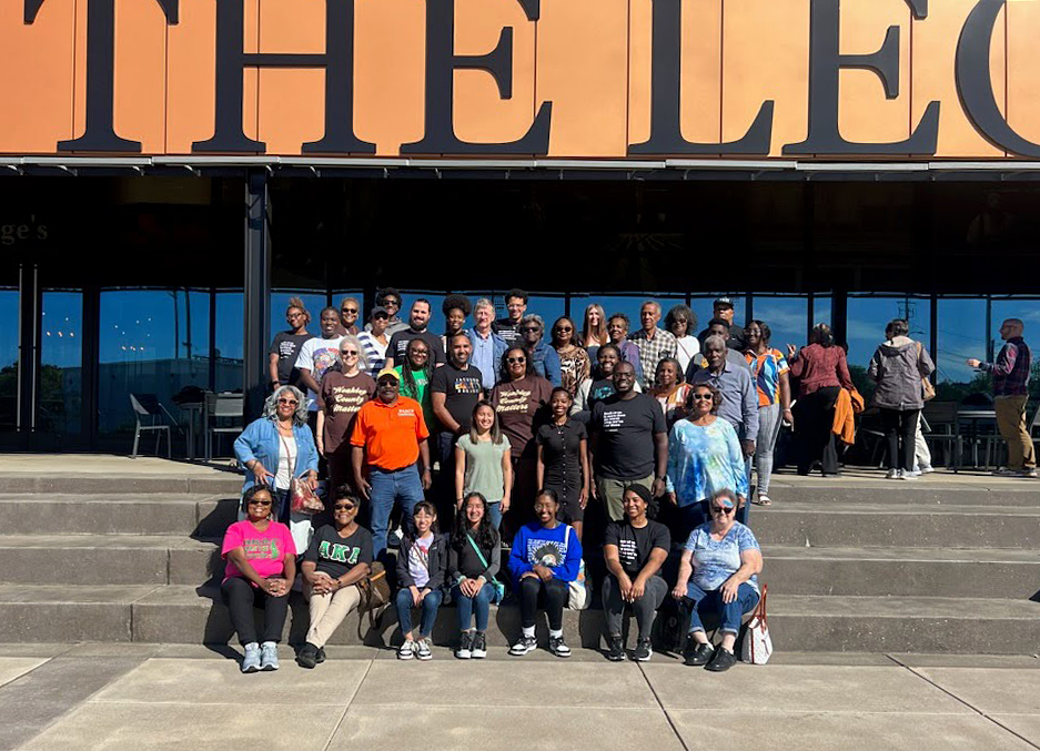 A group of people pose for a photo in front of the The Legacy Museum at the Equal Justice Initiative.